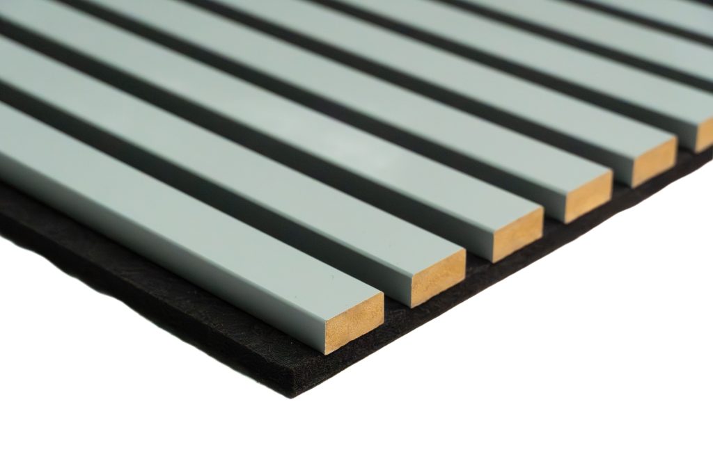 Close-up of a WoodUpp slatted acoustic panel: evenly spaced pale green-painted wooden battens with exposed raw end grain fixed to a thin black acoustic backing. The narrow rectangular slats form parallel grooves, showing the texture and precision of WoodUpp’s decorative acoustic slat product.
