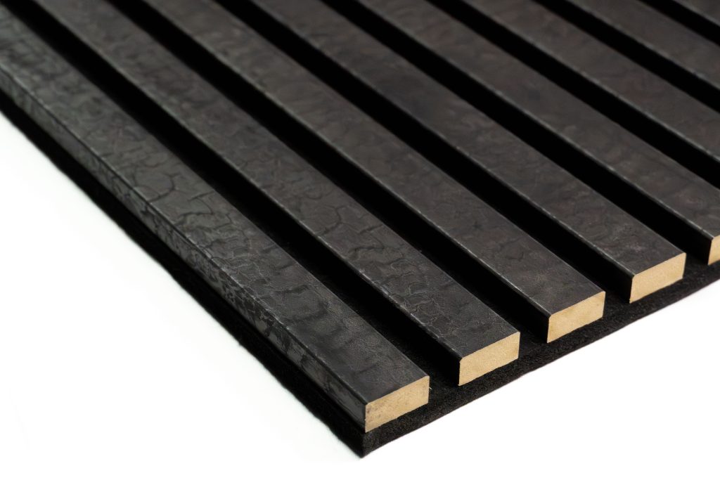 WoodUpp black acoustic slat panel showing parallel textured black wooden strips with exposed natural wood ends, mounted on a thin black felt backing. Close-up angle highlights uniform spacing, rectangular profiles, subtle hammer-textured surface and matte finish, emphasizing the product’s modern acoustic panel design.