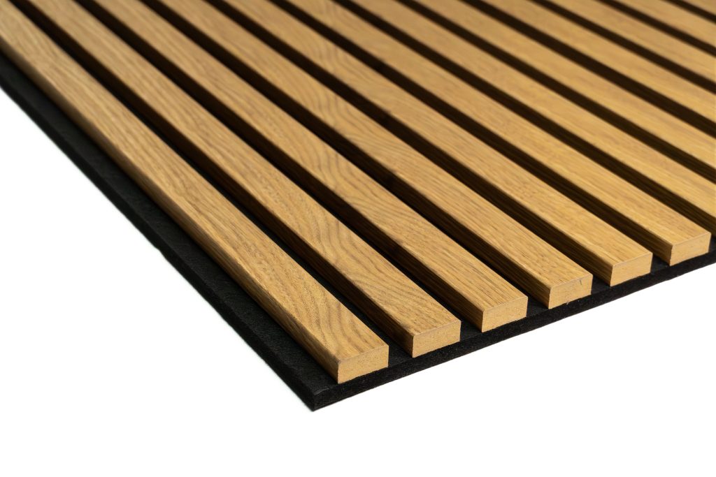 Close-up of a WoodUpp oak slatted acoustic panel: evenly spaced, rectangular light-oak wooden slats with visible grain, mounted on a black felt acoustic backing. The slats are slightly curved and aligned in parallel, showcasing WoodUpp's timber slat wall/ceiling acoustic product and texture.