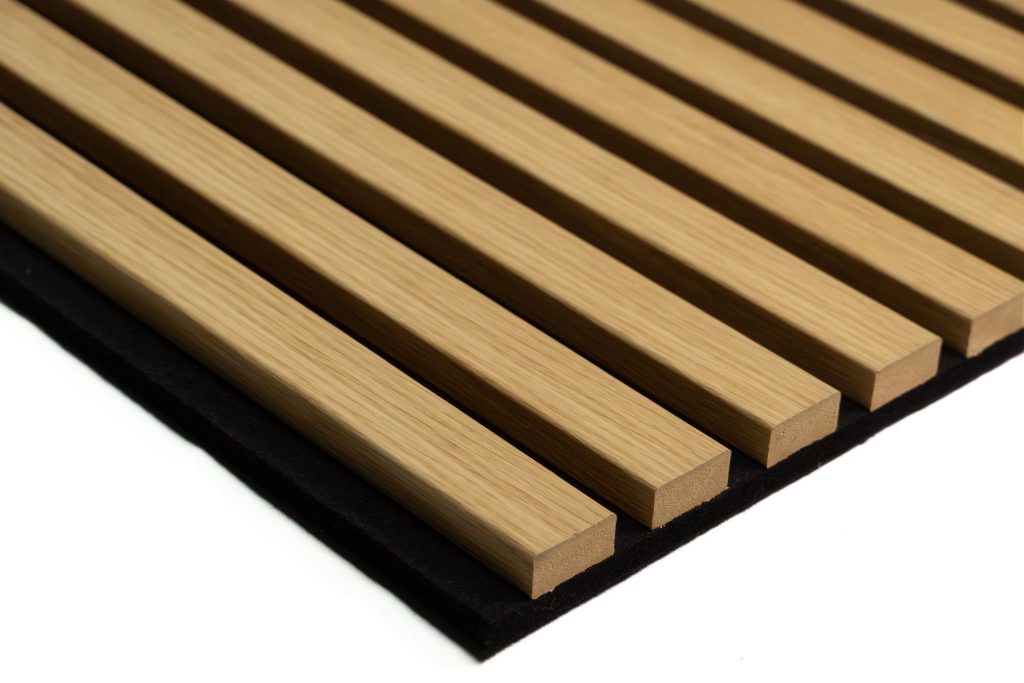 Close-up of a WoodUpp wooden slat acoustic panel: evenly spaced oak-finish rectangular slats with smooth rounded edges mounted on a black fabric backing, showing natural grain and light honey color, designed for decorative wall or ceiling installation and acoustic absorption.