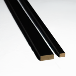 Two pieces of black WoodUpp termination trim are shown against a white background. One trim is wider than the other. Both have a smooth black finish on the visible surfaces and a reveal of the natural wood core at the cut ends.