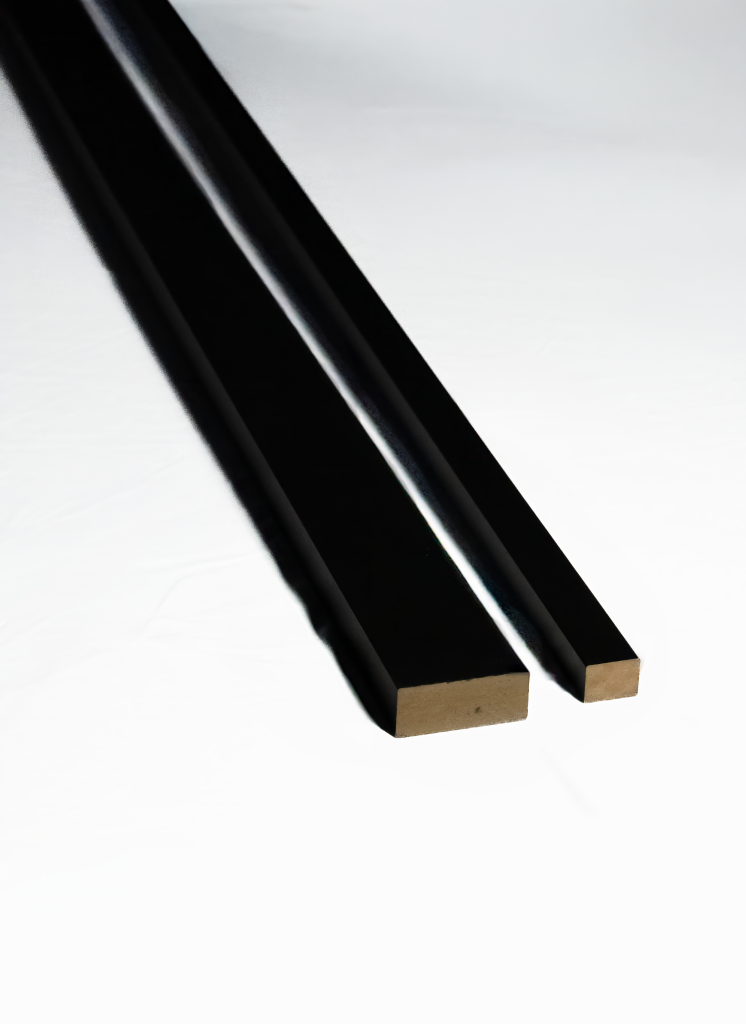 Two pieces of black WoodUpp termination trim are shown against a white background. One trim is wider than the other. Both have a smooth black finish on the visible surfaces and a reveal of the natural wood core at the cut ends.