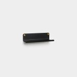 WoodUpp small black wall shelf with a slim horizontal lip and rounded backplate, mounted by two visible brass screws. Minimal matte metal design creates a narrow ledge suitable for keys, phones or mail. Simple modern wall-mounted storage and display from WoodUpp.