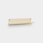 WoodUpp wall shelf: a minimalist beige metal floating shelf mounted on a white wall, featuring a slim ledge with front lip, rounded corners and two stainless steel mounting screws visible at each top corner. Clean, modern design for small items or décor.