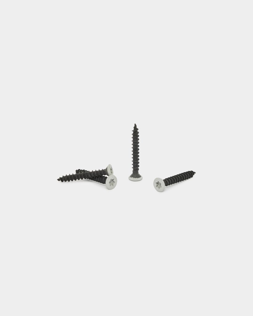 WoodUpp: four wood screws displayed on white background — three lying horizontally and one standing upright. Each screw has a black threaded shank and a silver, countersunk Phillips head, suitable for timber fixing. Product from WoodUpp shown clearly for scale and detail.