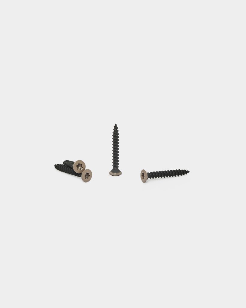 WoodUpp image of four WoodUpp decking screws on a plain white background: black, coarse-threaded wood screws with bronze-colored countersunk heads featuring a star (Torx) recess — two lying together, one standing upright and one angled — shown to highlight thread and head detail.