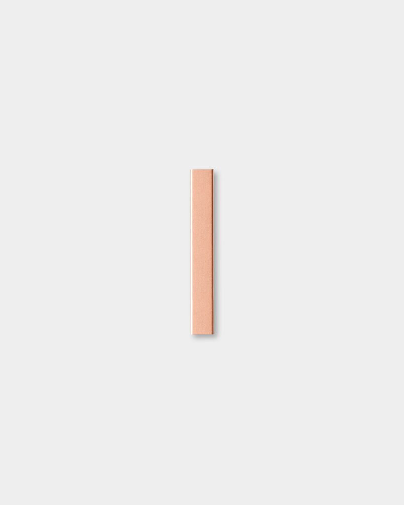Minimalist photograph showing a single WoodUpp product: a slim, rectangular wood repair stick in a warm peach-beige tone with subtle grain, positioned vertically and centered on a soft light-gray background, casting a faint shadow to emphasize its smooth, square-edged form.