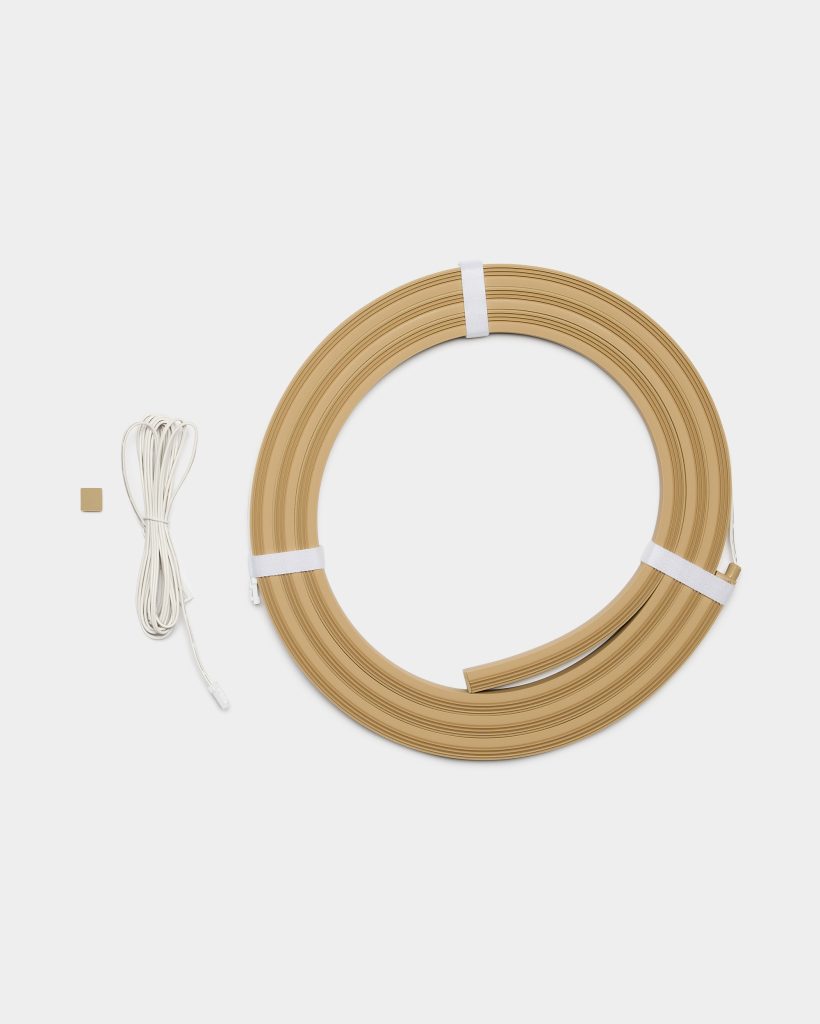 WoodUpp product image showing a coiled, light oak-coloured flexible wood edging strip with grooved profile, secured by white straps, accompanied by a long white LED connector cable and a small square adhesive mounting pad—components for installing WoodUpp’s illuminated wooden edge trim.