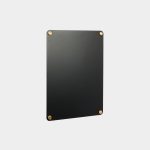 WoodUpp black rectangular wall board with a smooth matte finish shown against a pale background, fastened at each corner by four round brass mounting studs. The minimalist memo board appears thin and magnetic, ideal for notes or photos, showcasing WoodUpp’s modern, industrial design aesthetic.