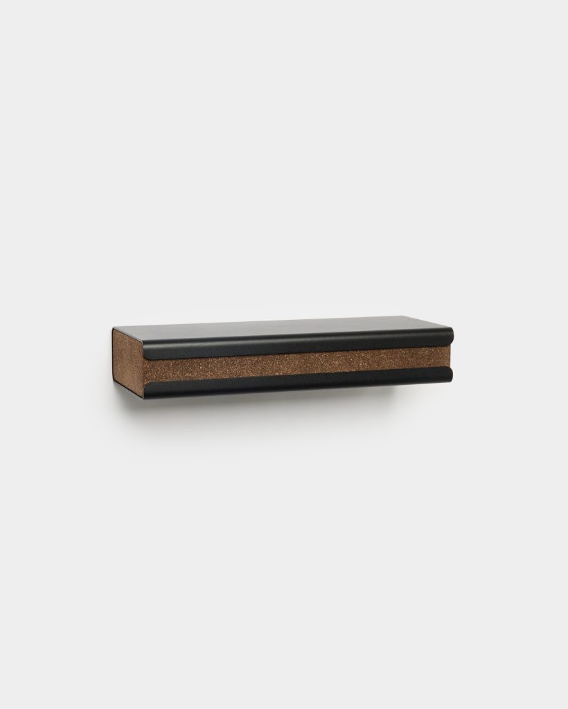 WoodUpp wall-mounted storage rail shown on a white background: a slim rectangular black metal rail with a central brown cork strip inset, rounded edges and a small shadow beneath, presenting a modern floating knife or tool rack combining metal durability with cork protection.