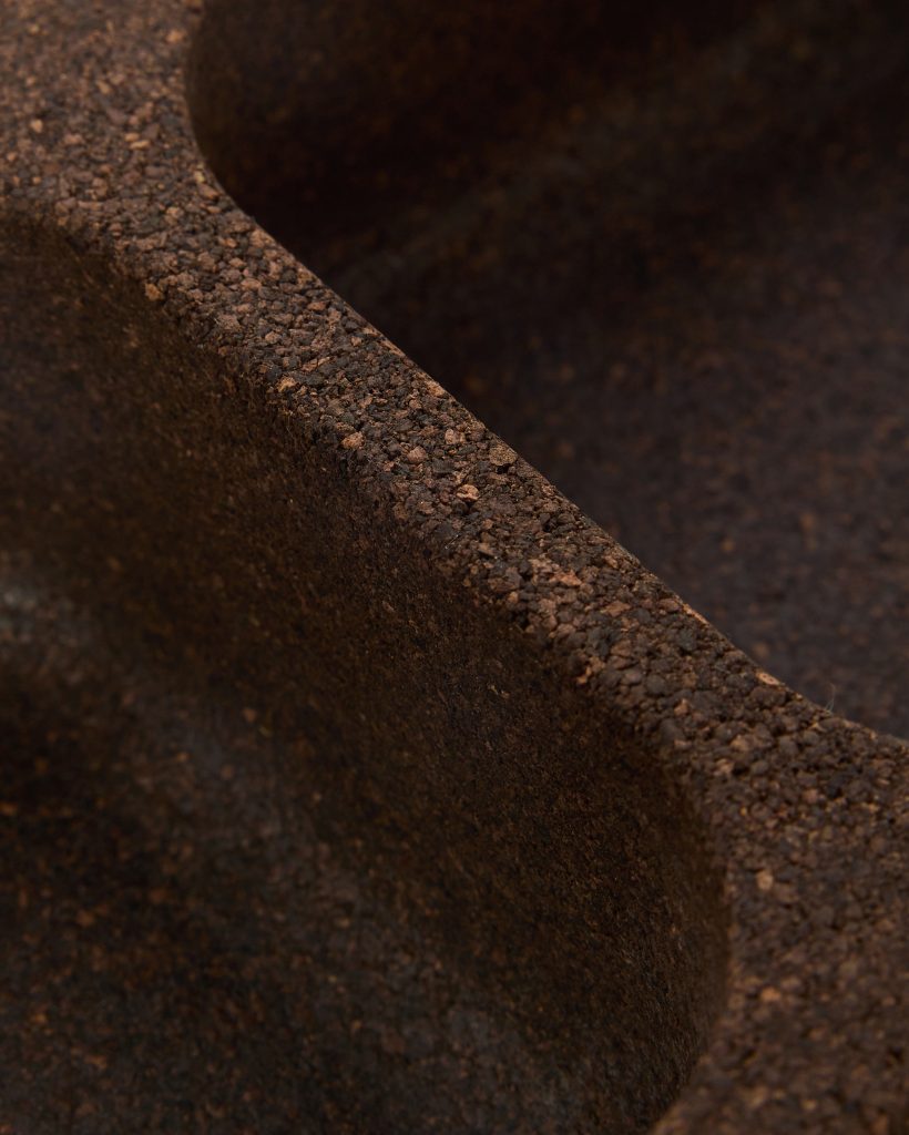 Close-up of a WoodUpp dark brown cork tray, showing textured, granulated cork edge and smooth inner curve. The photograph highlights the dense, sustainable cork material, rounded compartment divider and natural, earthy tones of WoodUpp’s modular cork organizer or serving tray.