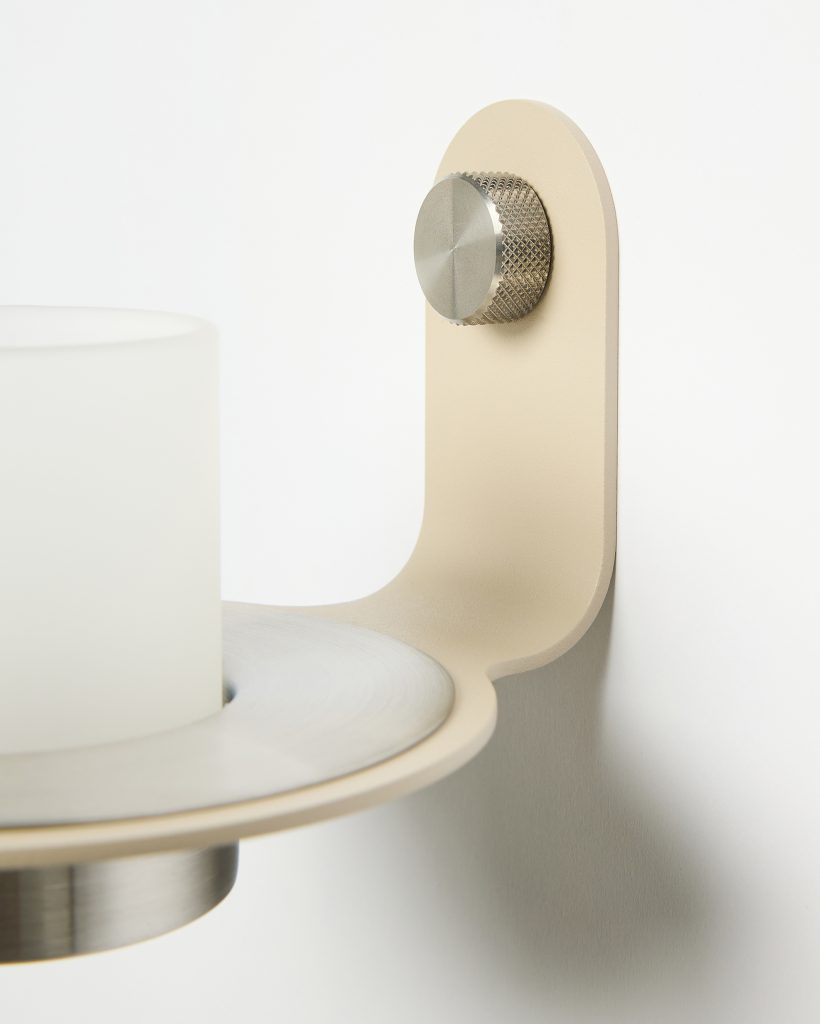 WoodUpp wall-mounted candle sconce featuring a beige powder-coated metal bracket, brushed stainless circular plate and knurled adjustment knob, holding a frosted glass votive cup. Close-up highlights the minimalist modern finish, smooth curves and precise metal detailing of the WoodUpp candle holder.
