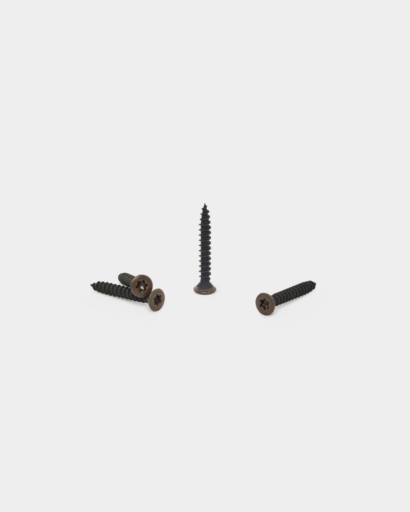 WoodUpp product image showing four black WoodUpp wood screws with brownish countersunk star-drive heads; one screw stands upright while three lie flat around it. Threads run full length to a sharp point, suitable for decking or timber fixing, photographed on a clean white background.
