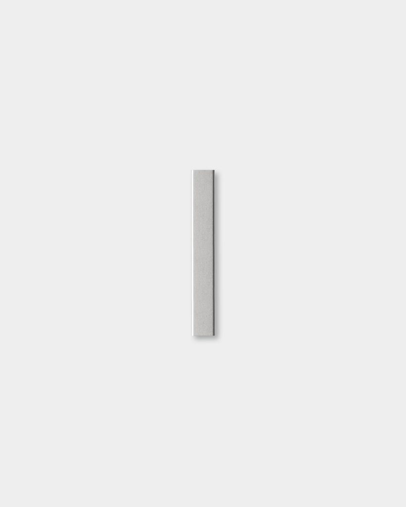 Minimal product shot for WoodUpp showing a single slim, brushed silver aluminum strip centered on a white background. The WoodUpp metal profile appears as a narrow rectangular bar with squared ends and a soft shadow beneath, emphasizing its clean, modern, architectural finish.