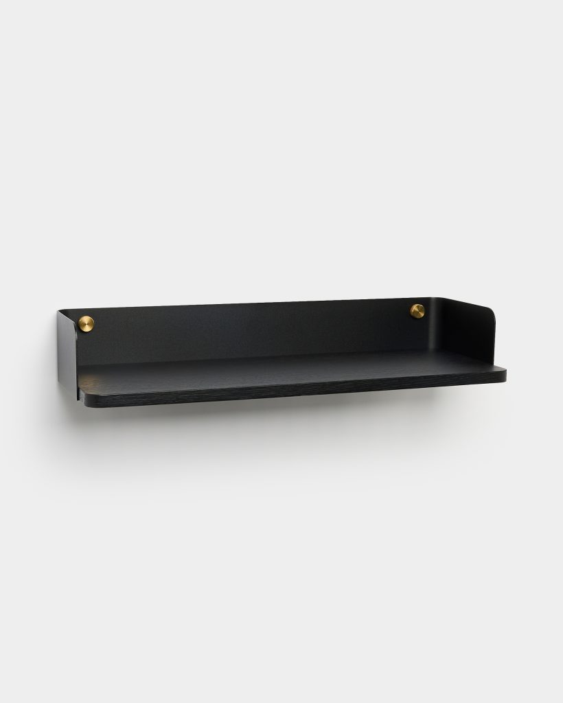 WoodUpp black wall shelf: minimalist wall-mounted shelf featuring a matte black metal backplate and floating black oak shelf, secured by two round brass studs at each end. Clean lines, slightly raised sides, and slim profile suitable for modern entryways or living spaces.