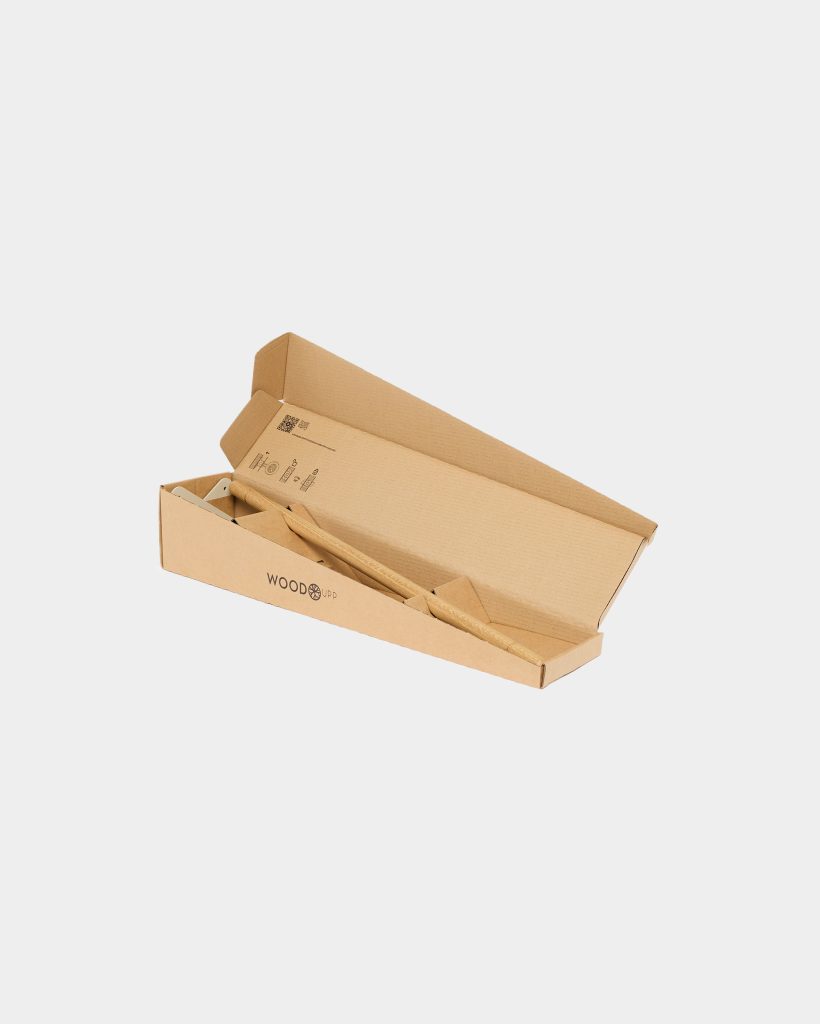 Open WoodUpp-branded kraft cardboard box holding a light oak wooden rod/dowel and two small wooden triangular spacers, plus a pale metal wall-mounting bracket. The components sit cushioned in die-cut cardboard inserts, showing an unassembled, minimal wooden wall hook or shelf hardware kit.